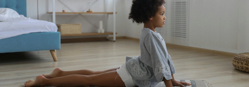 Little girl practising yoga, in cobra pose