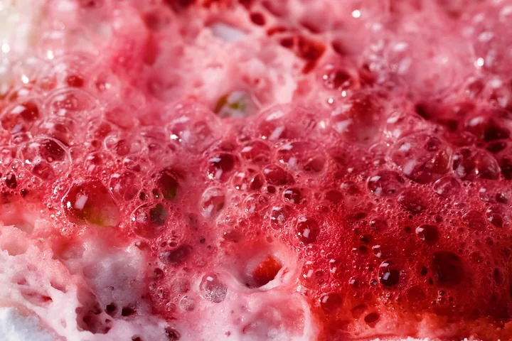 Close-up of red and white fizzing foam covered with bubbles.